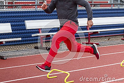 Motion blur on runner running fast over six inch hurdles on a track Stock Photo