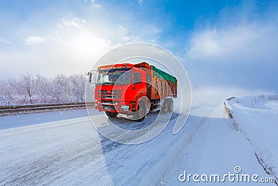 Motion blur of a red dump truck with cargo on winter road. Stock Photo