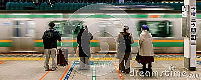 Motion blur of train arriving at Tokyo station transportation platform, Japanese people wait in line for boarding Editorial Stock Photo