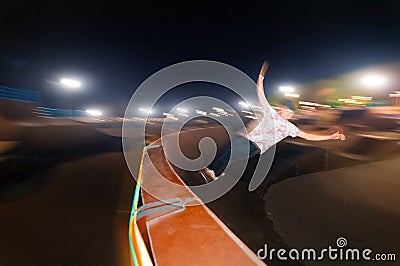 Motion in blur young skater is rolling down the ramp at night in a skate park. Flash technique with wiring movement Stock Photo