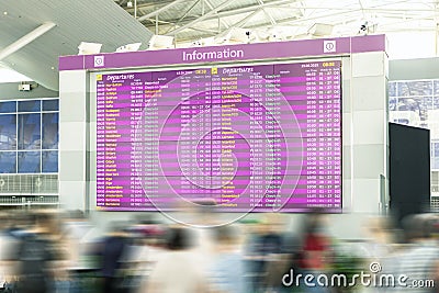 Motion blurred travellers crowd looking at fligh feparture and arrival timetable at airport terminal. Travel and tourism concept. Editorial Stock Photo