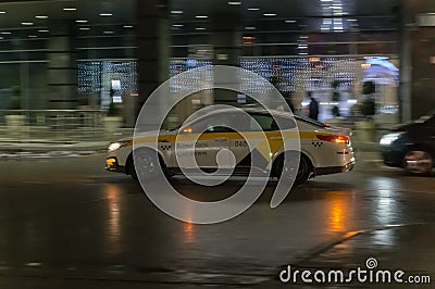 Motion city street scene with yellow taxi vehicle. Fast moving yandex taxi car on Moscow wet winter streets. Blured auto motion at Editorial Stock Photo