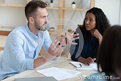 Motivated diverse colleagues discuss paperwork at meeting Stock Photo