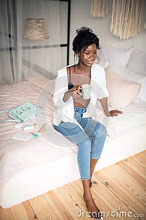 Smiling motivated woman drinking coffee after doing makeup Stock Photo