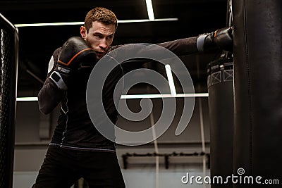 Motivated fighter practicing punches on heavy bag at boxing gym Stock Photo