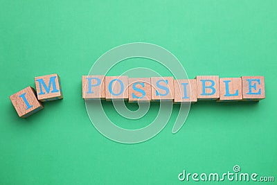 Motivation concept. Changing word from Impossible into Possible by removing wooden cubes with letters I and M Stock Photo