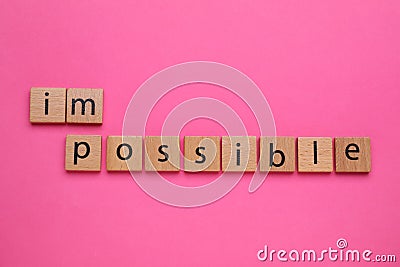 Motivation concept. Changing word from Impossible into Possible by removing wooden square with letters I and M Stock Photo