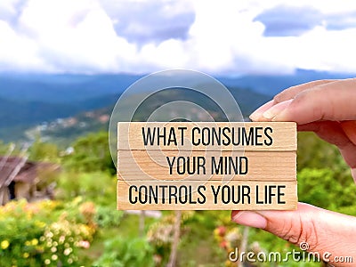Motivational inspirational quote. What consumes your mind, controls your life on wooden blocks with nature background. Stock Photo