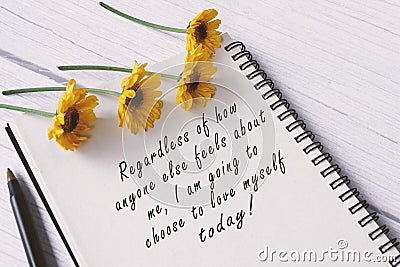 Motivational quote on note book with sunflowers on wooden desk. Stock Photo