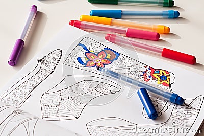 Motley pattern shoes and colour felt pens on table Stock Photo