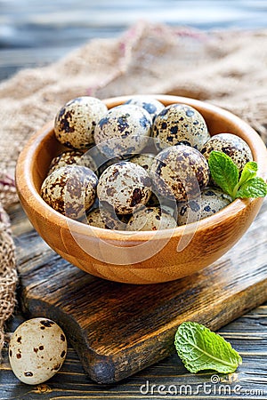 Motley quail eggs in a wooden bowl. Stock Photo