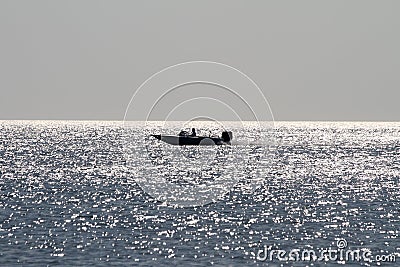A motor boat is floating on the sea on the horizon.The reflection of the sun on the waves.Infinite ocean. Stock Photo