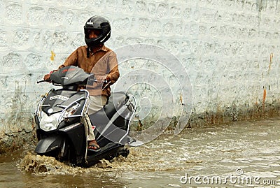 Motor Cyclist ride in rain water flooded road Editorial Stock Photo