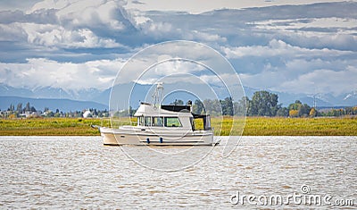 Motor ship at sunset sails on river. Powerboat on a water in overcast day Stock Photo