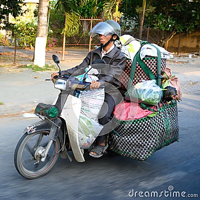 Moped rider Ho Chi Minh City or Saigon, Vietnam. Motorbike driver transporting goods and living hen on motorbike. Editorial Stock Photo