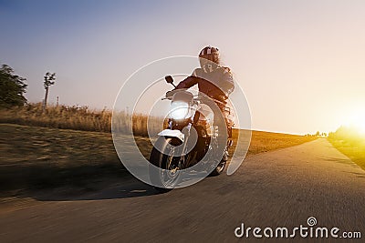 Motorbike drives on the road at sun dawn Stock Photo