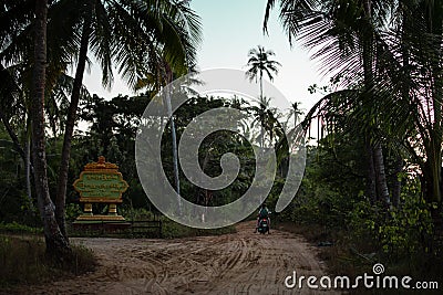 A motorbike drives on a sand road, Ngwesaung, Irrawaddy, Myanmar Stock Photo