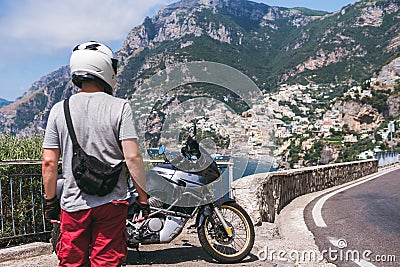 A motorbike traveler back view. On background incredibly beautiful view of Positano, a city on the edge of cliffs, the sea and a Stock Photo