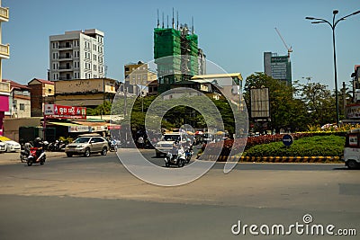 Motorbikes and cars on a roundabout in the middle of Phnom Penh City, Cambodia Editorial Stock Photo