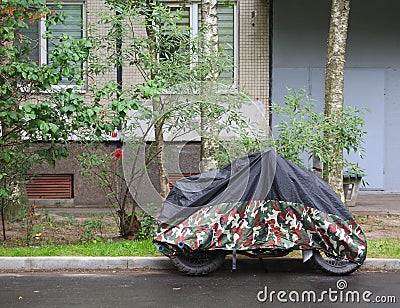 Motorcycle covered with a cover in bad weather Stock Photo