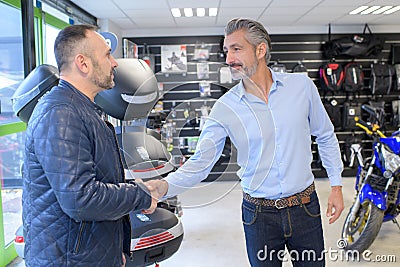 motorcycle dealer shaking hands with customer entering shop Stock Photo