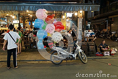The motorcycle with fancy balloons for sale parks in front the bar and restaurant in Hue city, Vietnam. Editorial Stock Photo