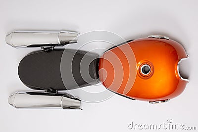 Motorcycle tank orange with black seat and chrome silver mufflers exhaust part motorbike in flat lay top view Stock Photo