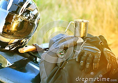 Motorcyclist helmet, gloves, knife, compass and other accessories lie on the seat of a motorcycle. Stock Photo