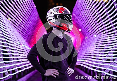 A motorcyclist in helmet stands among many lanterns. A lot of light effects. Middle of the light street. Night city Stock Photo