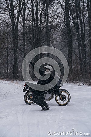 Motorcyclist man dancing with happiness near adventure motorcycle. Winter snow fall. off road dual sport crazy extreme ride, Stock Photo