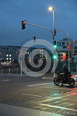 Motorcyclist with retro motorcycle standing in front of a green traffic light in Heerdt Editorial Stock Photo