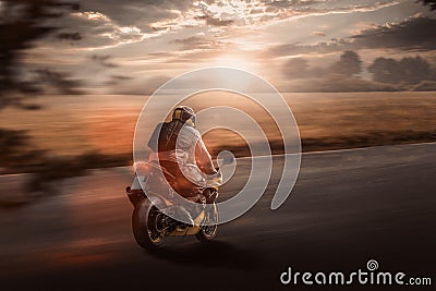 Motorbike drives fast on the road in the evening glow Stock Photo