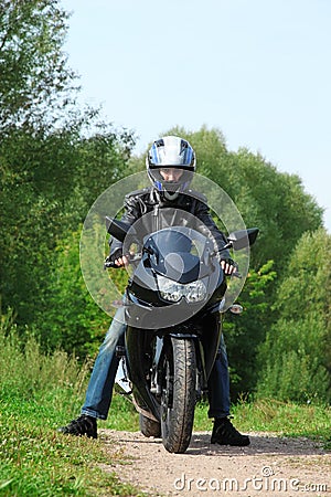 Motorcyclist standing on country road Stock Photo