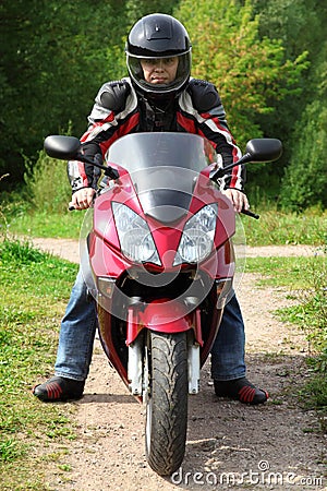 Motorcyclist standing on country road Stock Photo