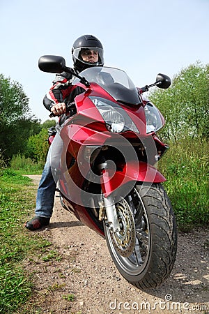 Motorcyclist standing on country road Stock Photo