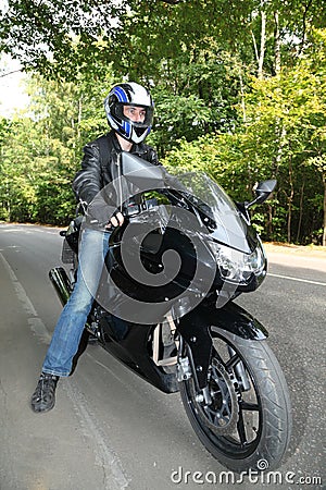 Motorcyclist standing on road Stock Photo