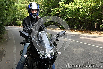 Motorcyclist standing on road Stock Photo