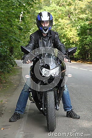 Motorcyclist standing on road Stock Photo