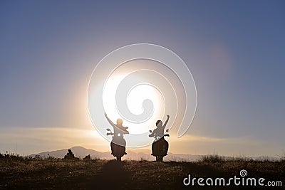 Motorcyclists waving at sun Stock Photo