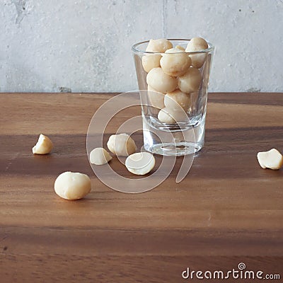 A mound of organic Macademia nuts on a rustic wooden table Stock Photo