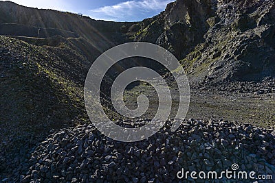Mounds of stones and rock piles, with rocky outcrops, in a disused quarry, blue sky with clouds Stock Photo