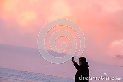 Mount Elbrus, Russia, Man takes a picture on the phone in the mountains during sunset Editorial Stock Photo