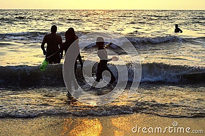 Mount Lavinia Beach. Colombo, Sri Lanka. 05th March 2016. Silhouette of a family enjoying a bath at the beach with the sunset ba Editorial Stock Photo