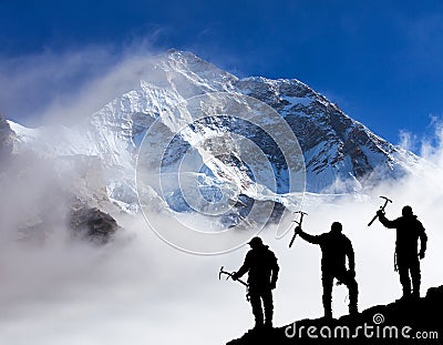 Mount Makalu with clouds and silhouette of three hikers Stock Photo