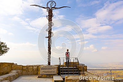 Woman standing next to The Brazen Serpent, religions christian cross, overlooking the promised and holy land in the distance Editorial Stock Photo