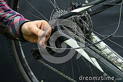 Mountain bike repair in the workshop. Mechanic's hands and tool close-up. The mechanic cuts off the old rear derailleur Stock Photo