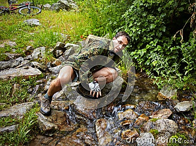 Mountain Biker drinking from a stream Stock Photo