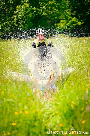 Mountain Biker Riding Through A Large Puddle Stock Photo