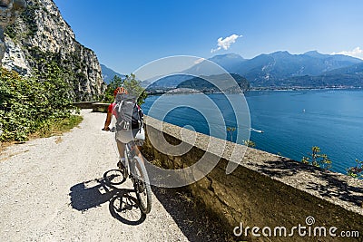 Mountain biking at sunrise woman over Lake Garda on path Sentiero della Ponale, Riva del Garda, Italy Stock Photo