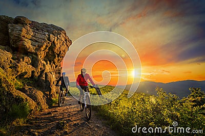 Mountain biking women and man riding on bikes at sunset mountain Stock Photo